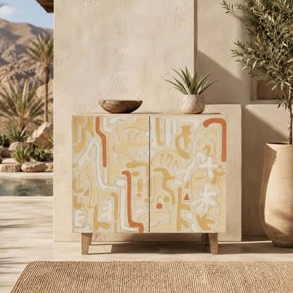 A two-door sideboard cabinet with an abstract mid-century modern pattern in cream, tan, and terracotta orange, styled in a sunlit outdoor patio setting with plants and a bowl on top.